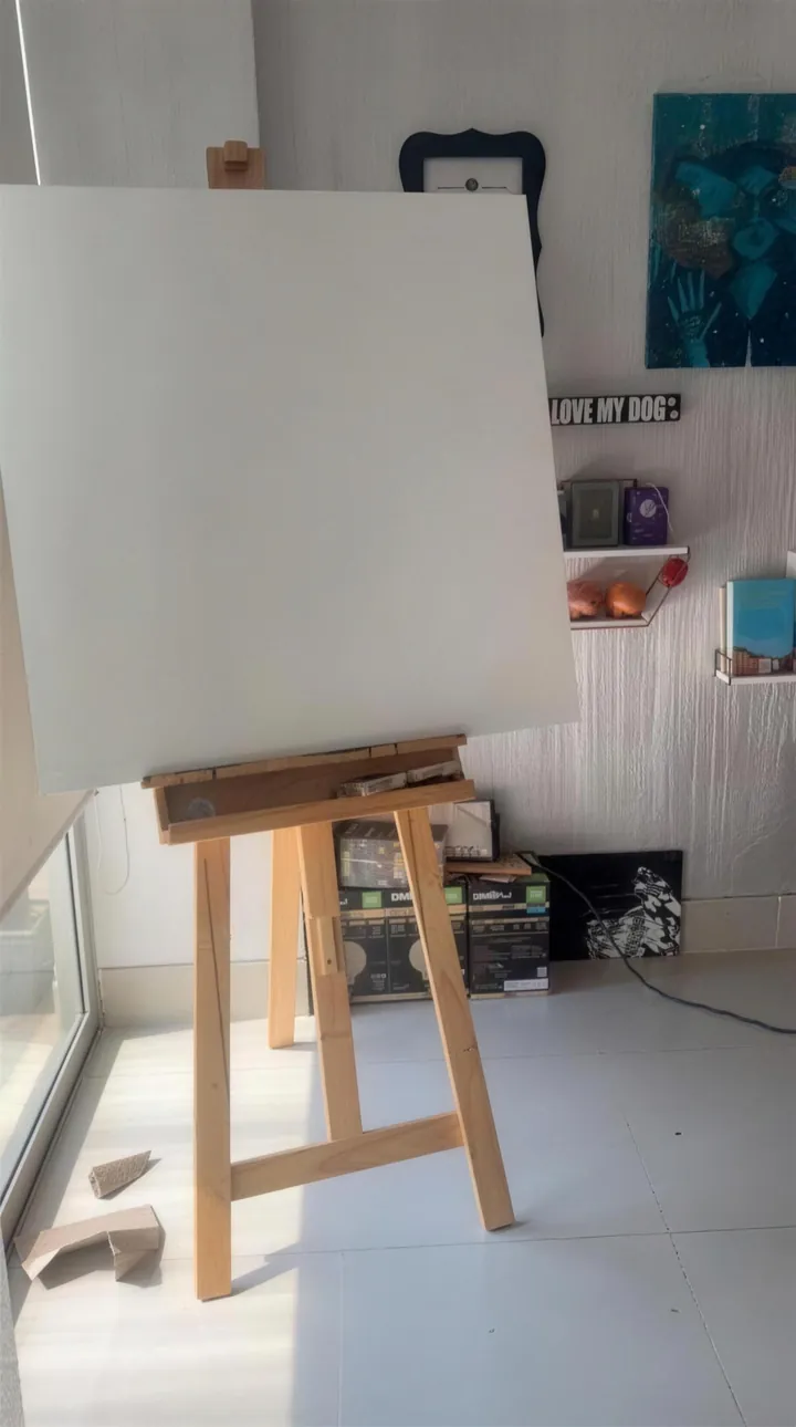 Un lienzo en blanco en el caballete, en el taller con luz de ventana.