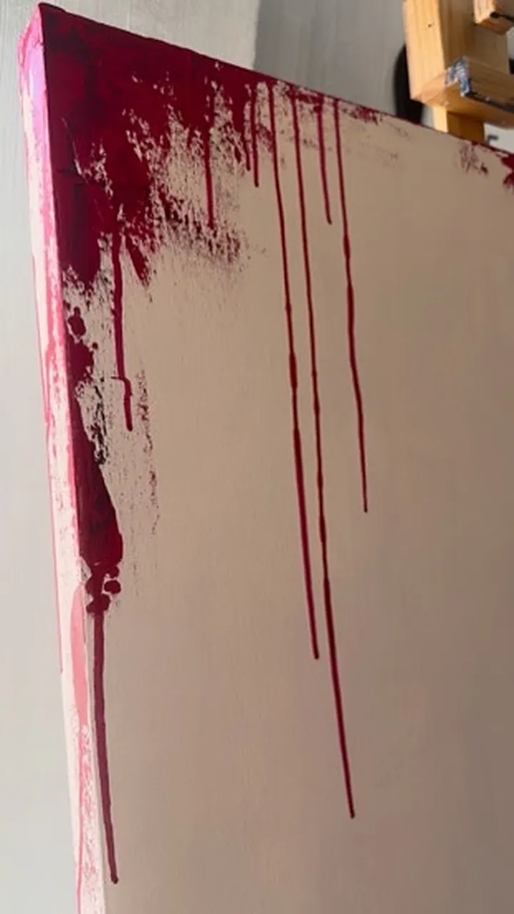 Pintura roja que gotea desde el borde del lienzo.